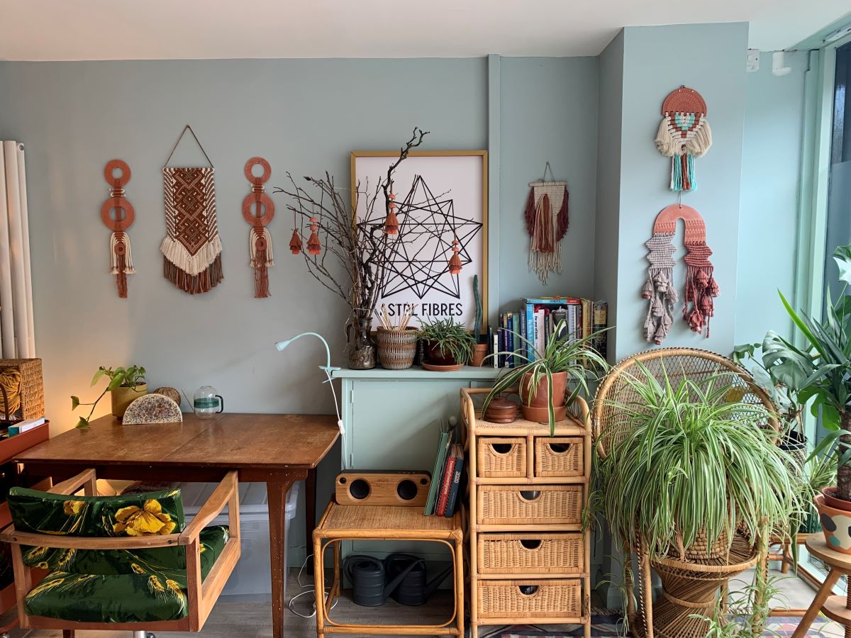 Stylish room interior with a desk, chairs, plants, macramé artworks and woven baskets in a  cosy artist studio setting.