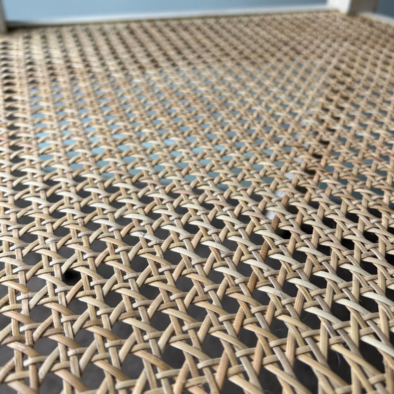 Close-up of a 6 way woven rattan cane chair seat surface with a blurred background